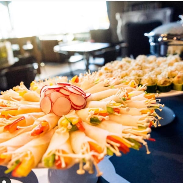 Platter of Korean BBQ rolls with colorful vegetables and enoki mushrooms, garnished with radishes.